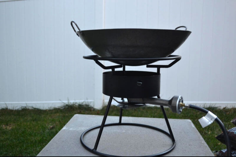 Carbon steel wok on an outdoor high output gas range.
