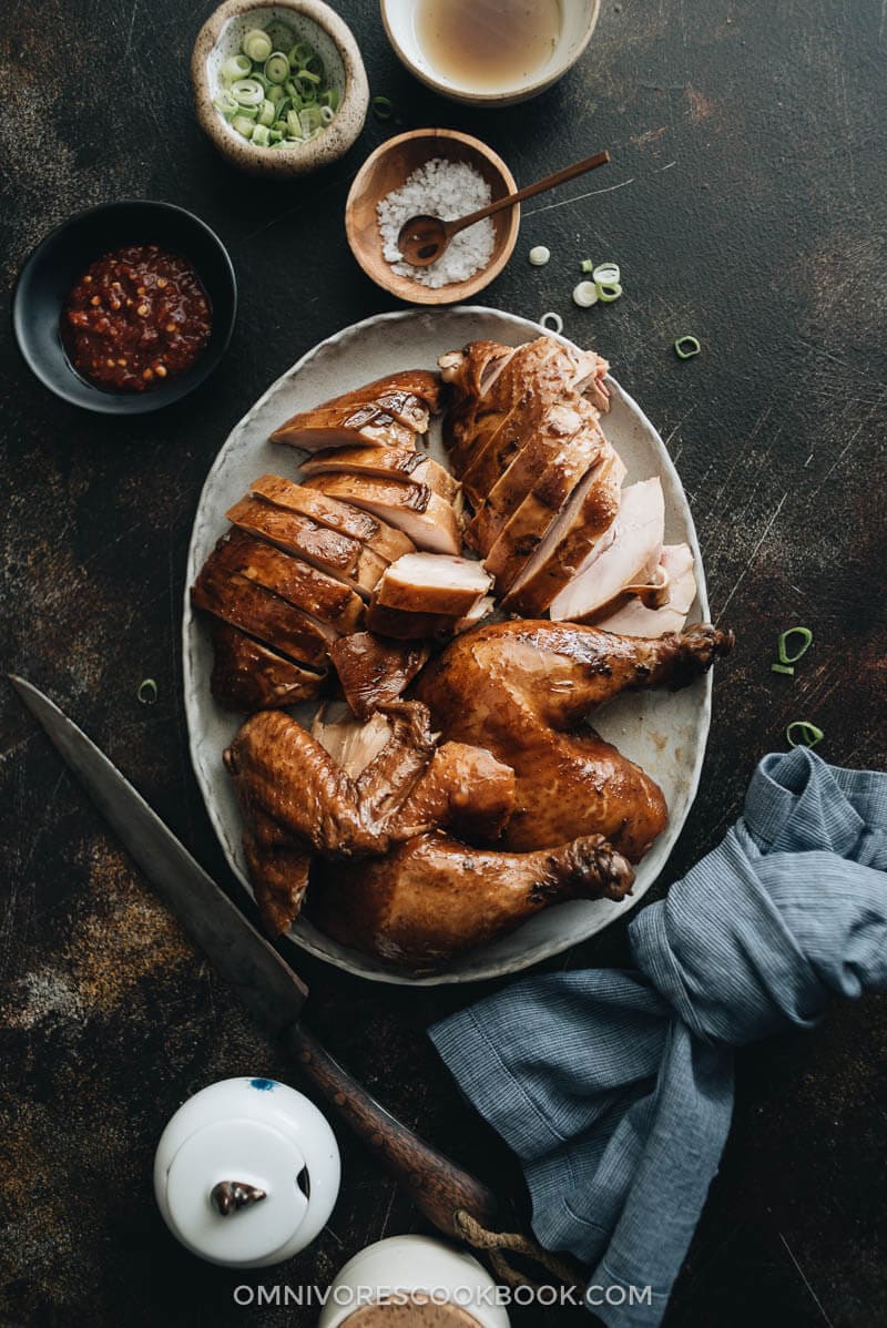 Sliced soy sauce chicken served with Sriracha, salt, and green onions