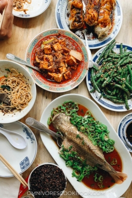 A Sichuan Chinese dinner spread with whole fish, mapo tofu, green beans, and eggplant