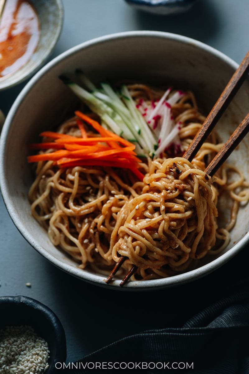 Closeup of nutty Chinese noodles in a bowl with chopsticks