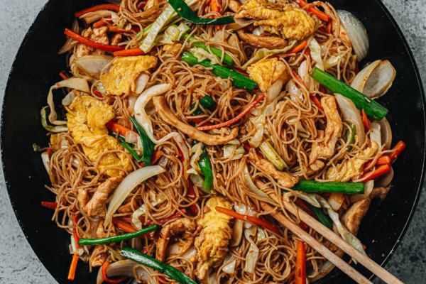 Stir fried rice noodles with chicken, eggs and vegetables in a pan